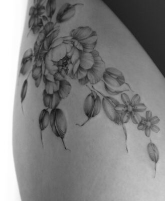Fine line floral tattoo of hips, with peonies and leaves, tattooed at Vadelma Tattoo studio in Amsterdam